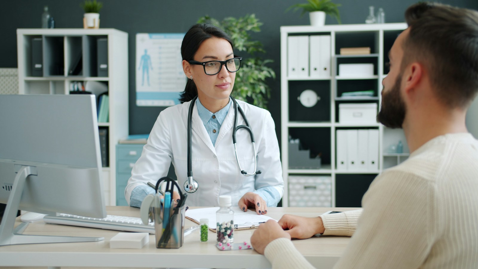 A physician reviewing a treatment plan with a patient across a desk in a clinic office
